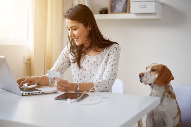 Kvinna med dator sitter med en hund bredvid
